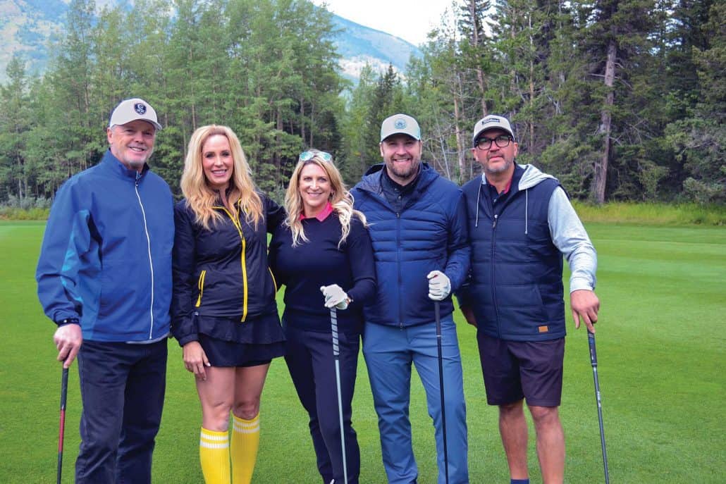 Group of adults standing with golf clubs. 