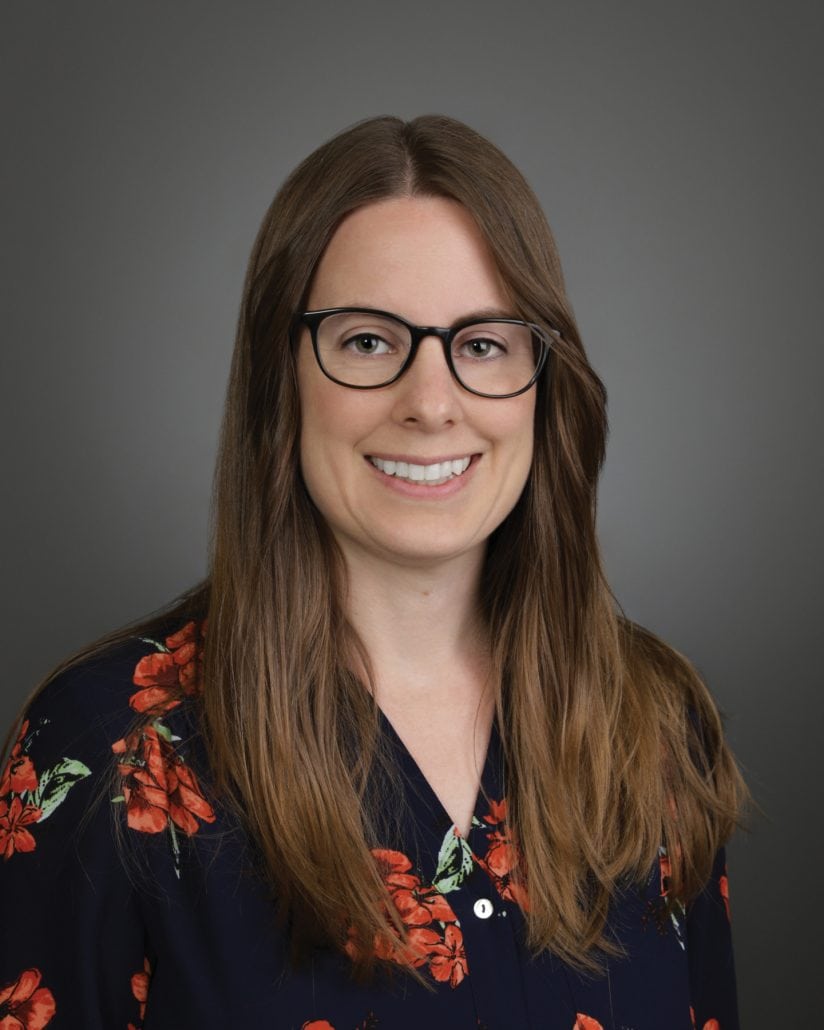 Portrait of a woman in a flower shirt smiling at the camera. 