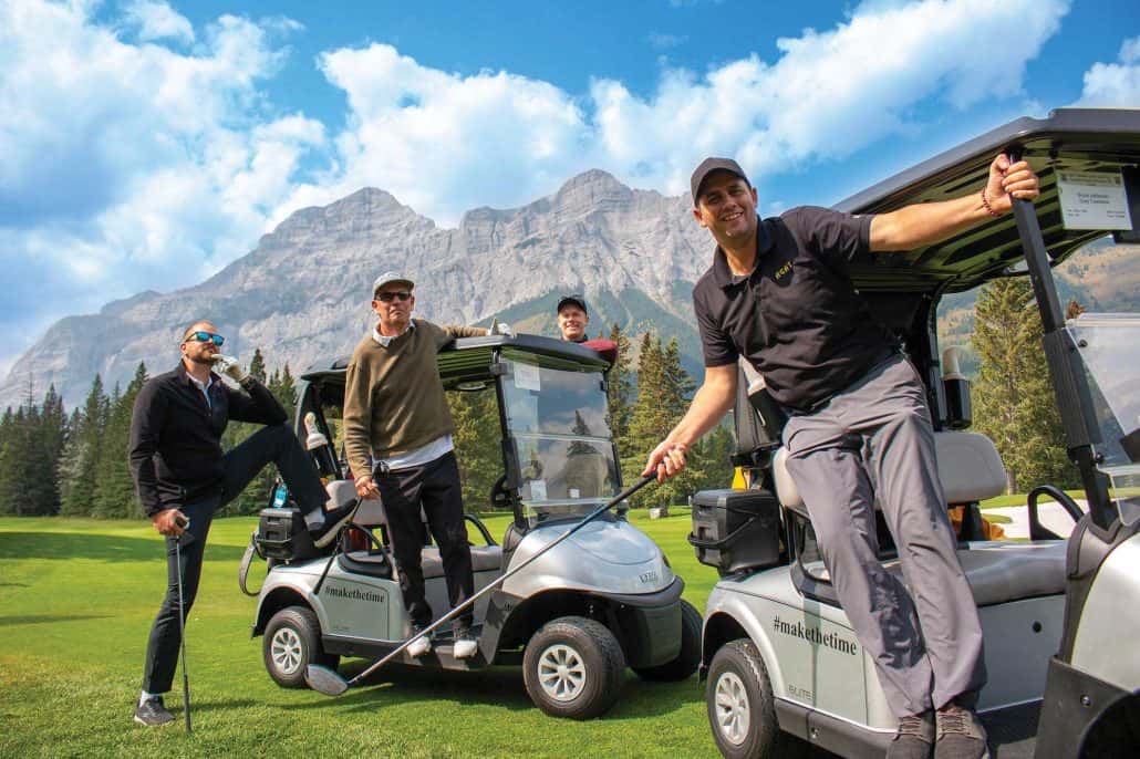 Men standing on gold carts with mountains in the background.
