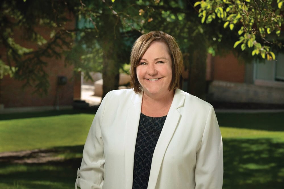 Woman in a white blazer smiling.