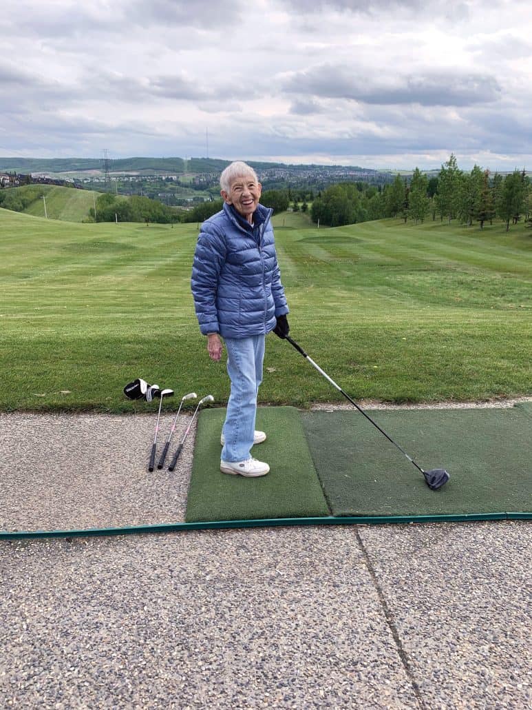 Woman smiling at the camera preparing to hit a golf ball. 