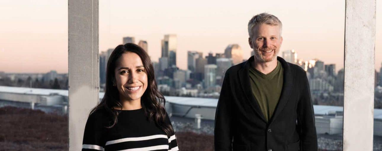 A man and a woman standing in front of a window with the view of the city.
