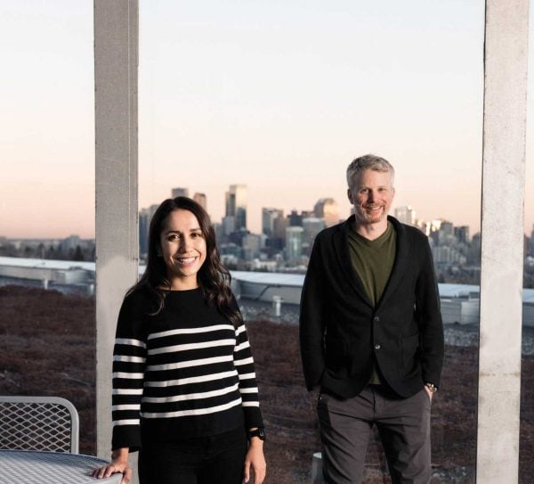 A man and a woman standing in front of a window with the view of the city.