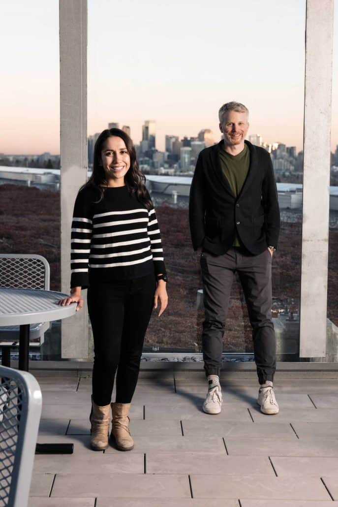 A man and a woman standing in front of a window with the view of the city.