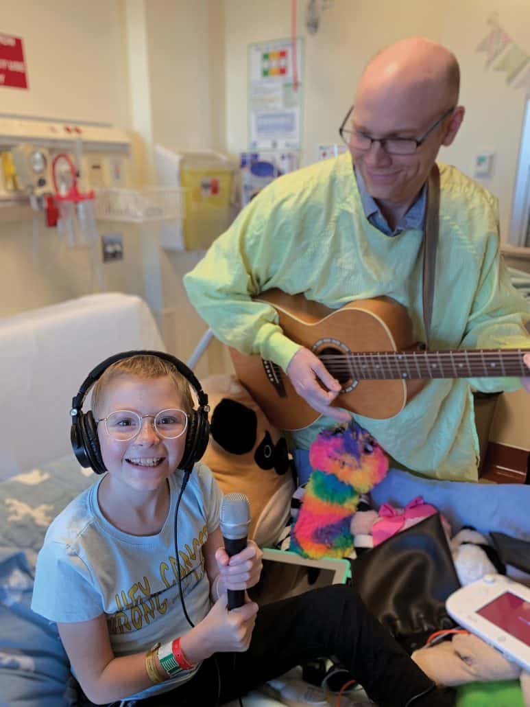 Young cancer patient making music with a music therapist.