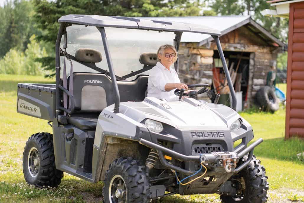Woman in white driving a side-by-side off-road vehicle. 