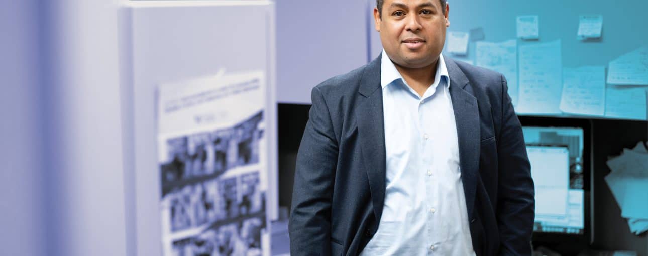 Man in an office standing with his hands in his pockets.