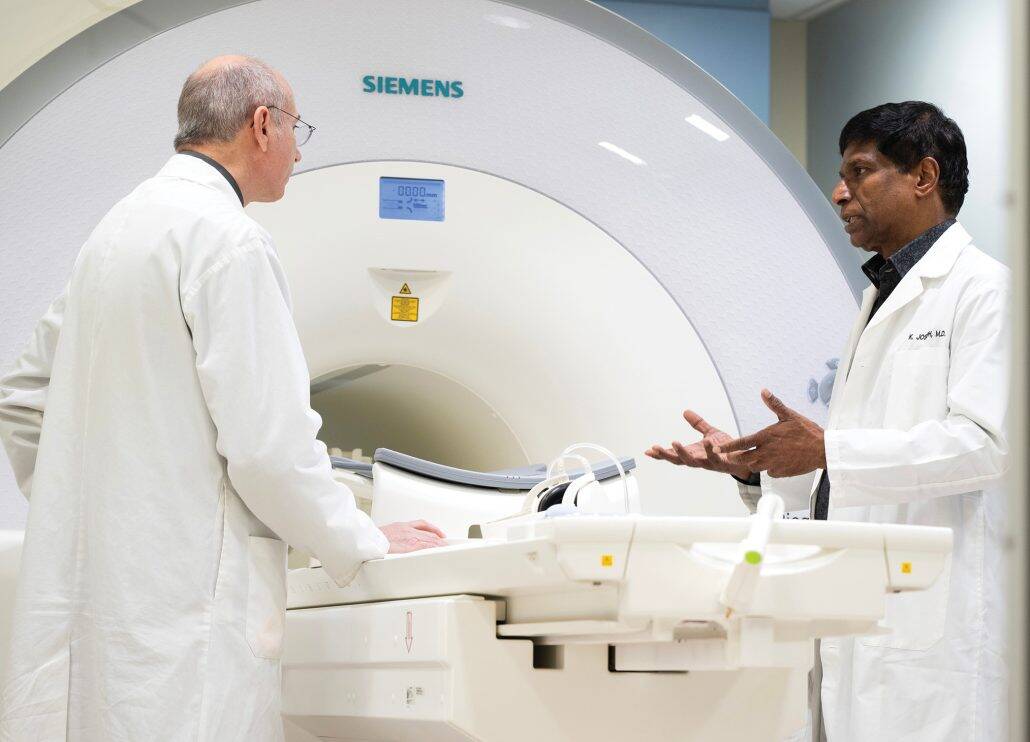Two doctors consult each other in front of a radiation machine. 