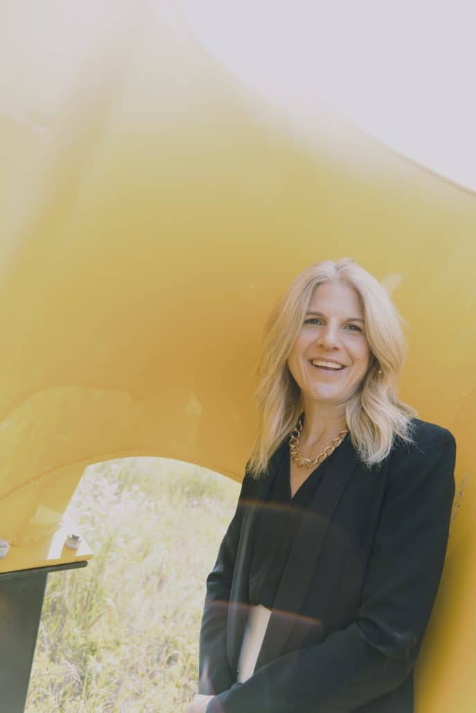 Woman in a black blazer against a yellow background.