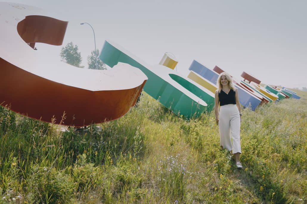Woman walking un grass by. the Alberta Children's Hospital sign.