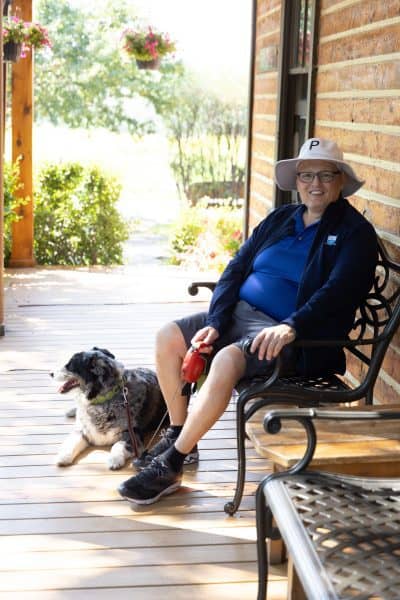 Man sitting on a bench with his dog by his feet.