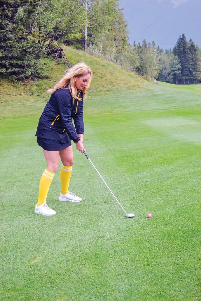 Woman about to hit a golf ball.