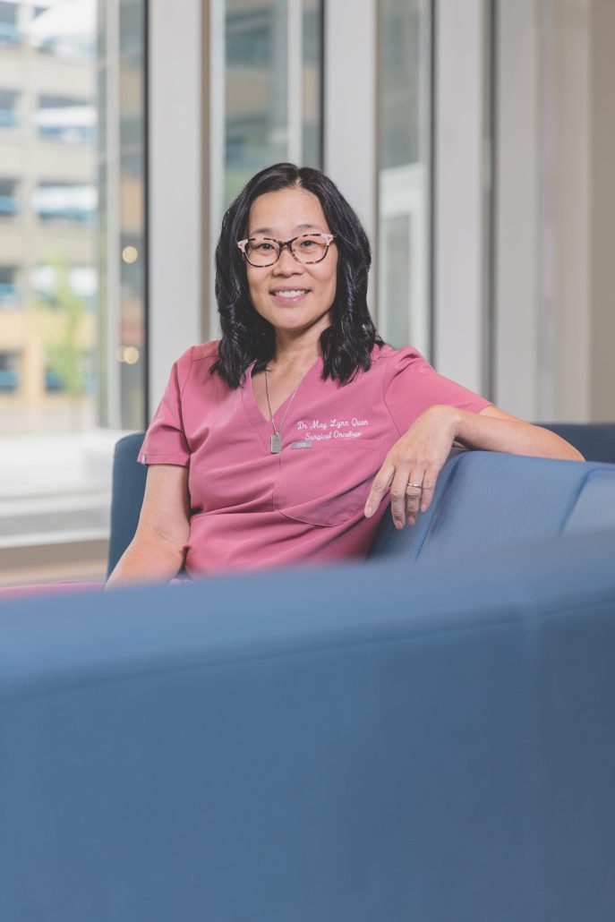 Doctor in pink scrubs sitting on a blue couch.