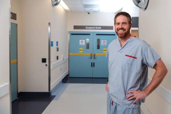 Doctor in scrubs standing in a hospital hallway.