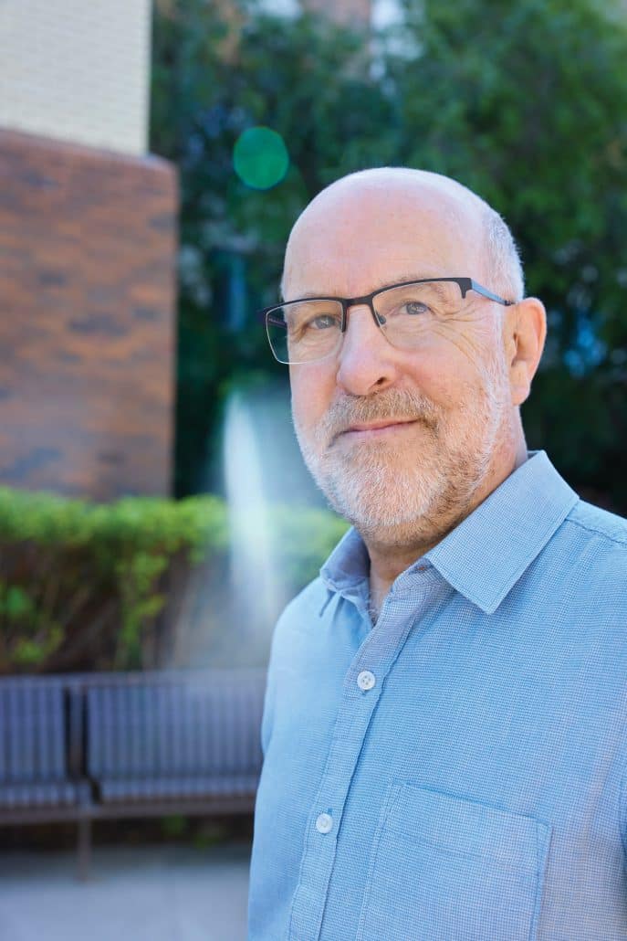 Man with glasses in a blue shirt looking into the camera.