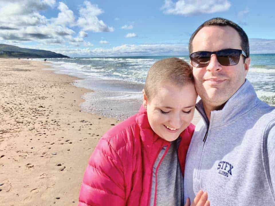 Woman in pink jacket with a man in a sweater on the beach.