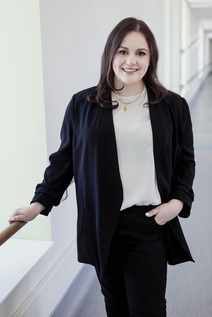 Woman smiling into the camera while holding a railing.
