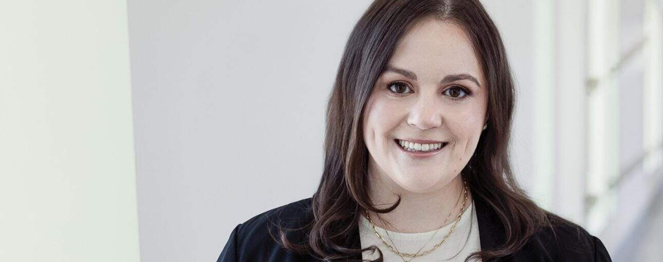 Woman smiling at the camera wearing a black blazer.