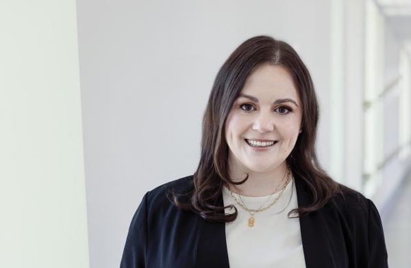 Woman smiling at the camera wearing a black blazer.