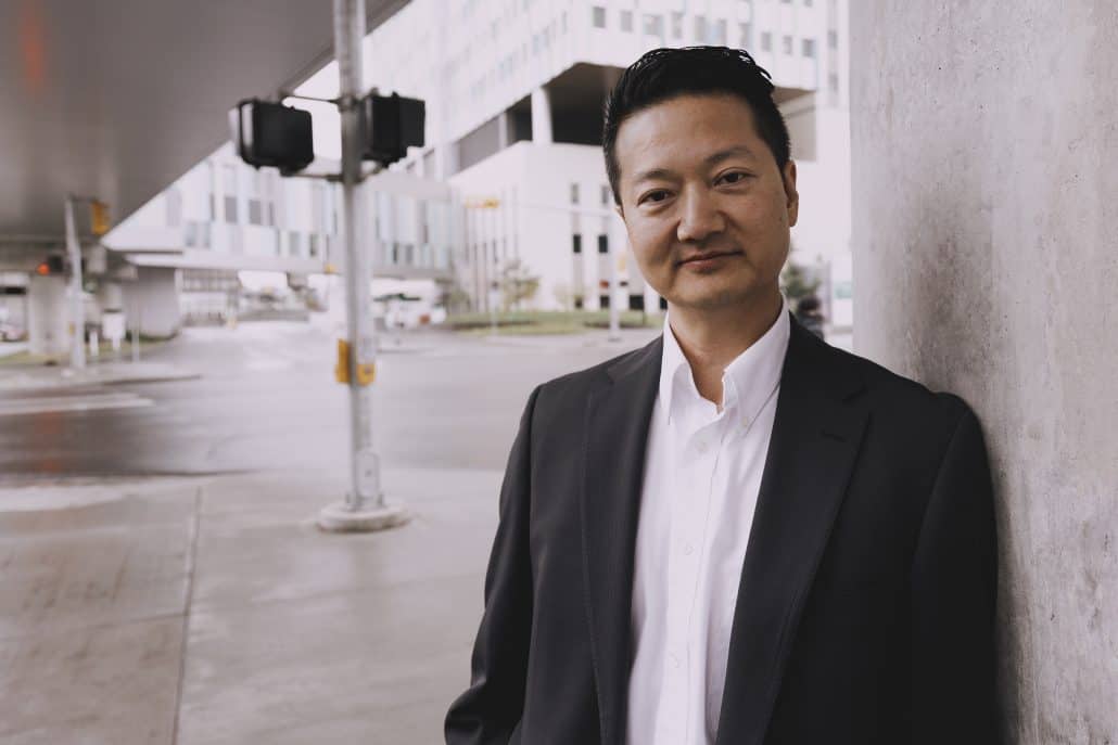 Man leaning against a wall outside with a street light behind him.
