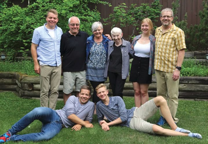Group image of a family with two member laying down on the grass and the rest standing behind them.
