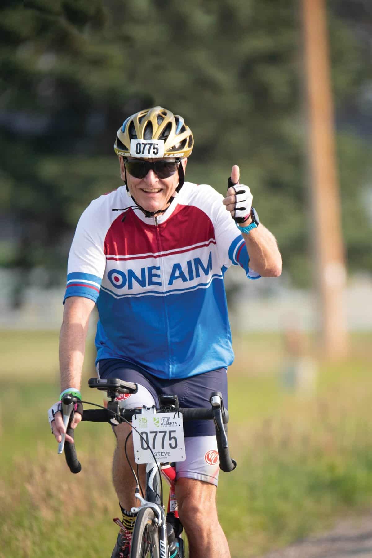 A man gives a thumbs up while riding his bike.