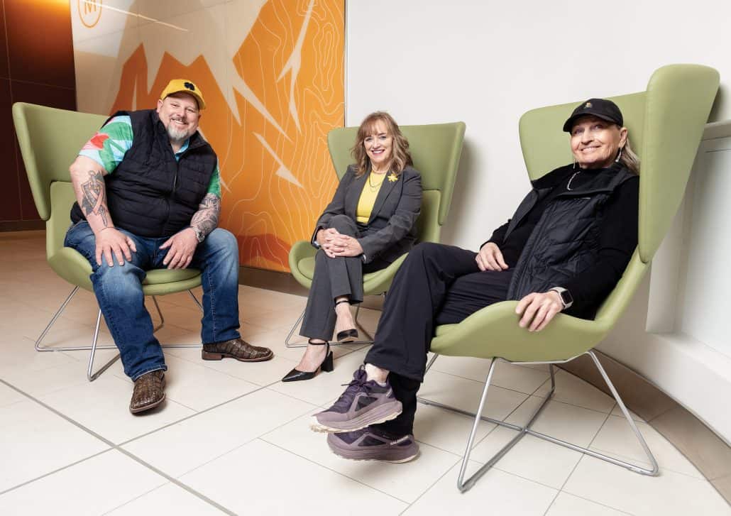 A man and two women sit in three large green chairs.