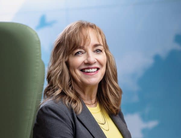 Woman sitting in a green chair smiling at the camera.