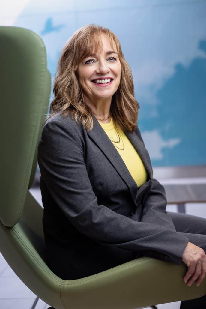 Woman sitting in a green chair smiling at the camera.