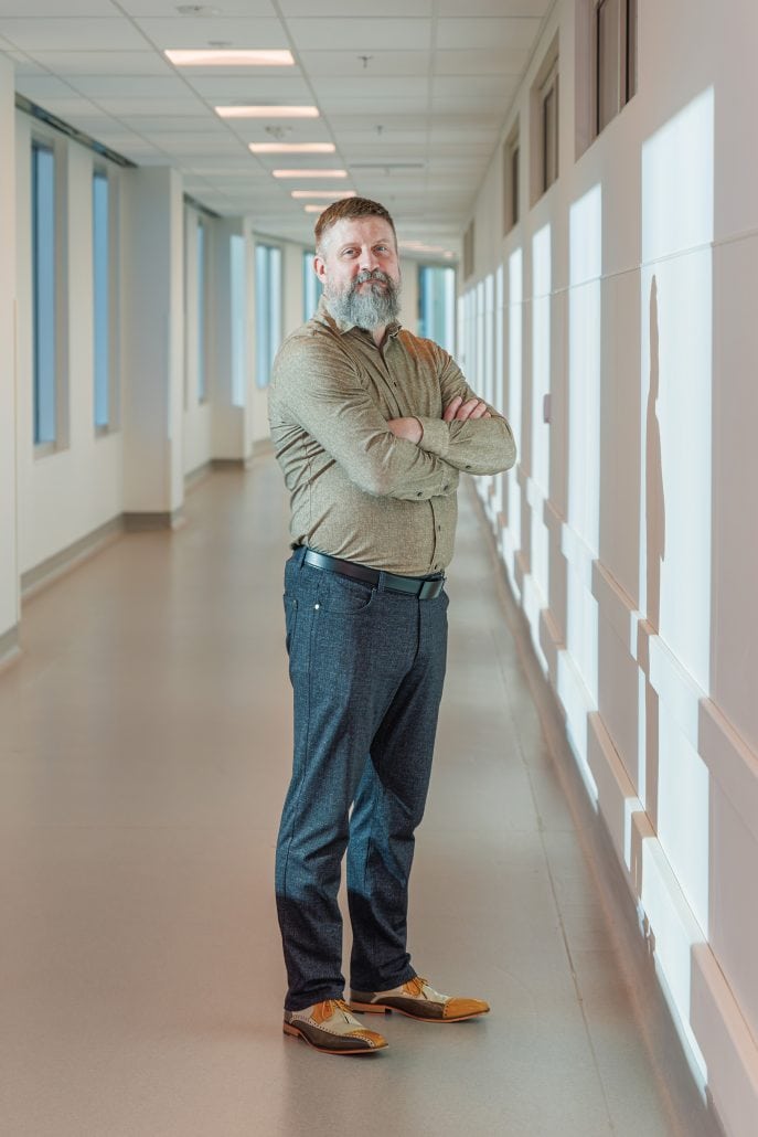Man standing in a hallway with his arms crossed. 